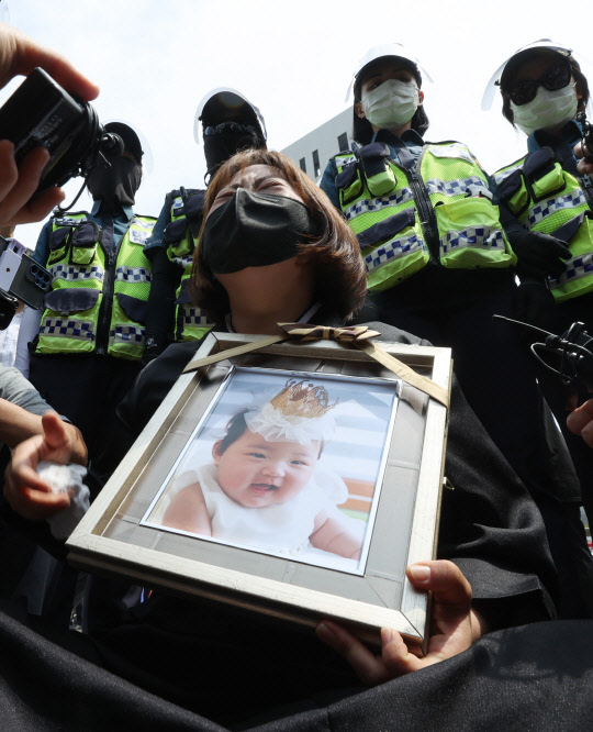 16개월 된 입양아 정인 양을 학대해 숨지게 한 혐의를 받는 양부모의 1심 선고 공판이 열린 14일 오전 서울 양천구 서울남부지법 앞에서 정인 양의 사진을 끌어안은 시민이 눈물을 흘리고 있다.  연합뉴스